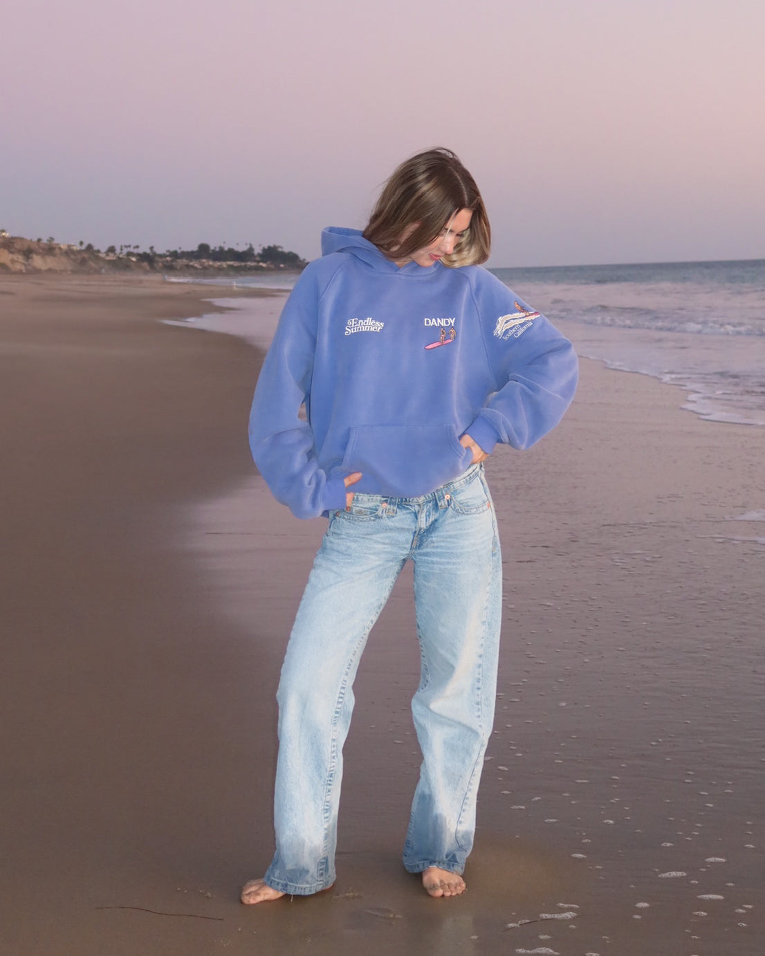"Endless Summer" Oversized Lux Hoodie in Vintage Washed Blue showing the front of the hoodie on the beach