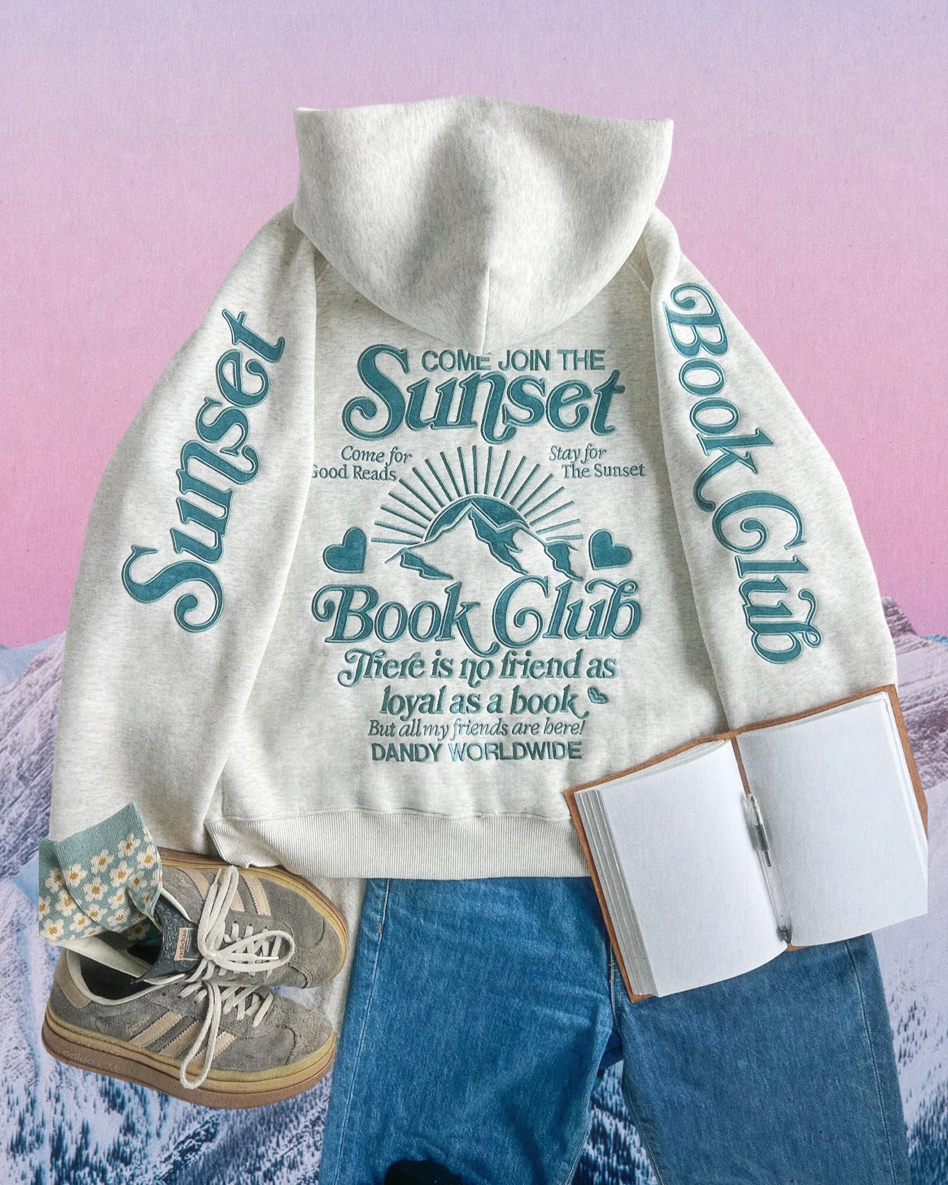 Photo shows a flat lay of a heather gray book club hoodie, blue denim jeans, and gray Adidas against a graphic background of a mountain.