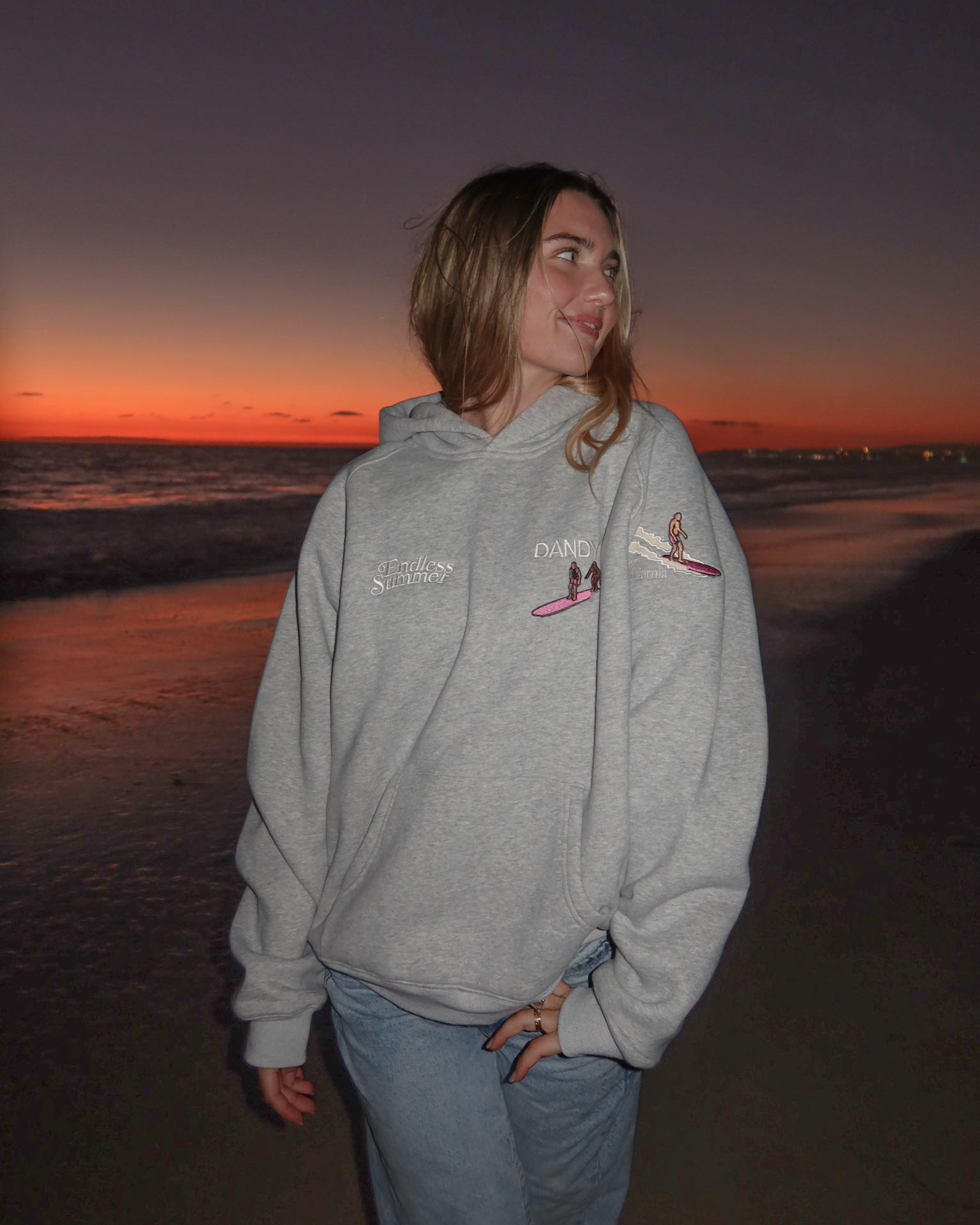 "Endless Summer" Oversized Lux Hoodie in Dark Heather showing the front of the hoodie on the beach at sunset