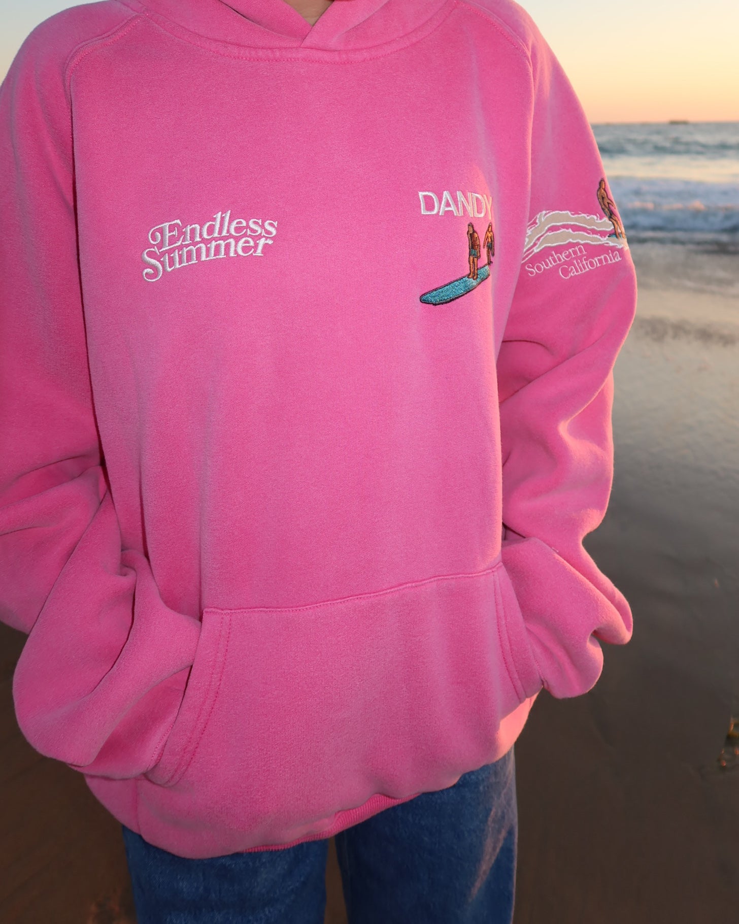 "Endless Summer" Oversized Lux Hoodie in Vintage Washed Pink showing the front of the hoodie on the beach