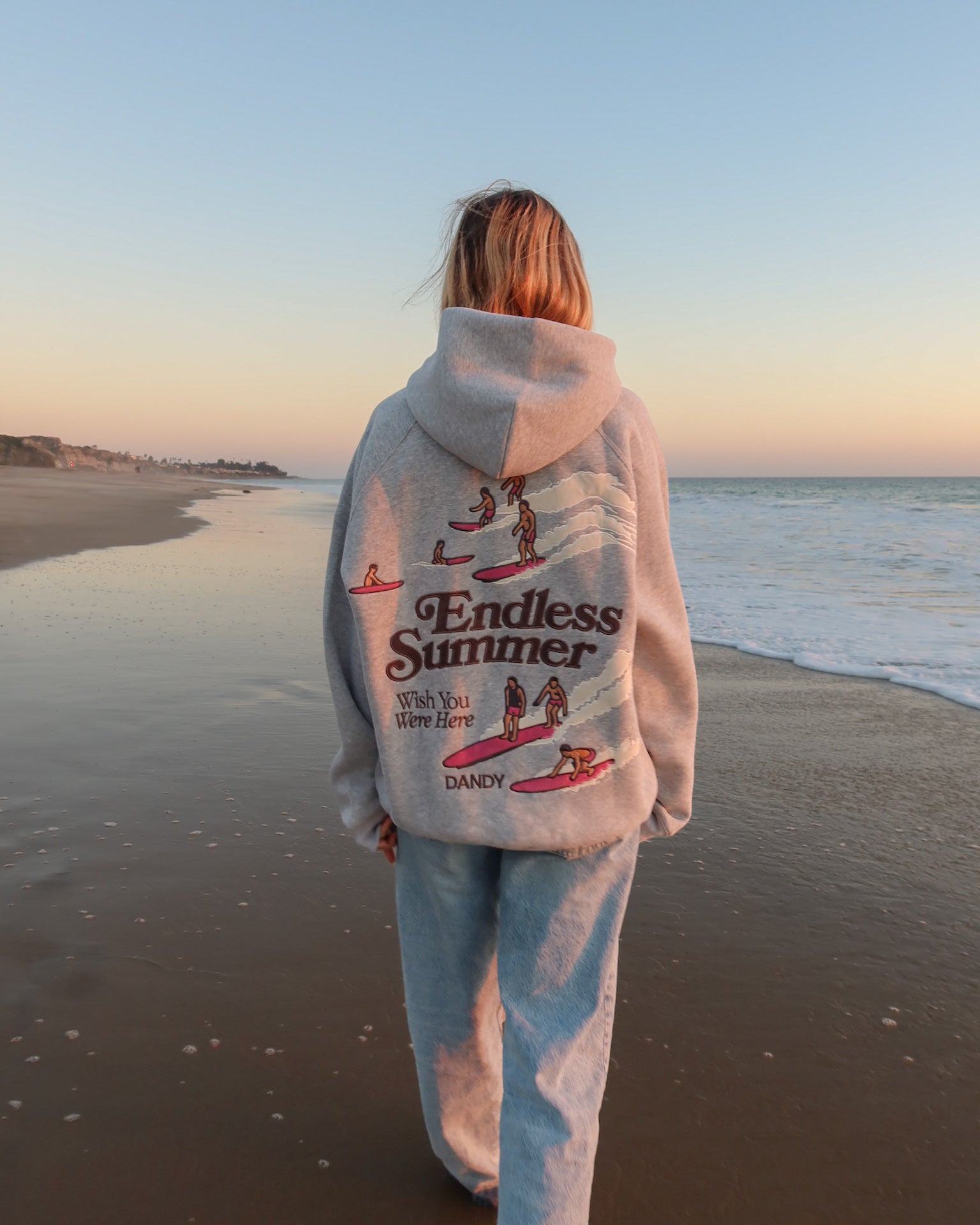 "Endless Summer" Oversized Lux Hoodie in Dark Heather walking on the beach at sunset
