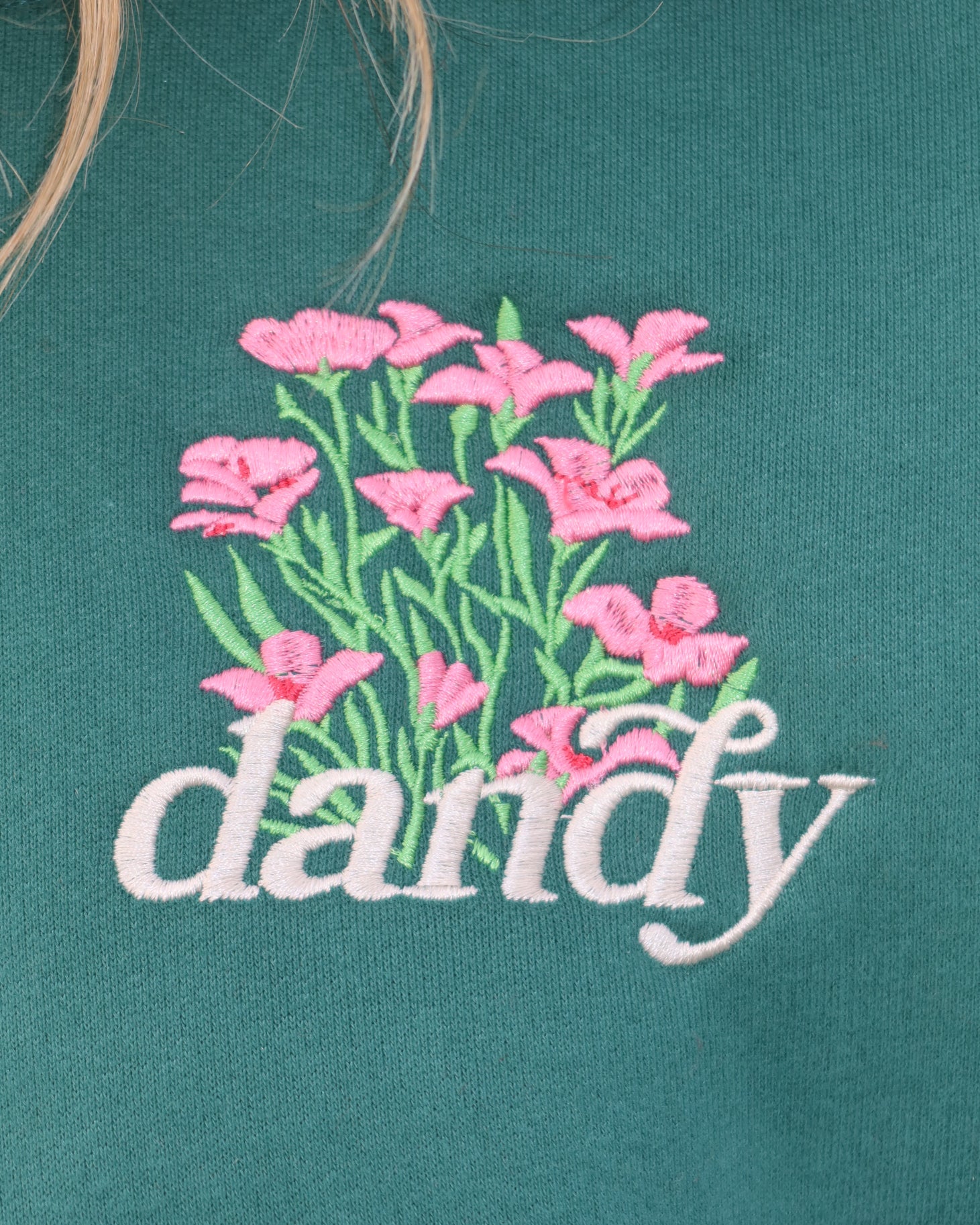 Embroidered pink flowers and the word 'dandy' on a green background