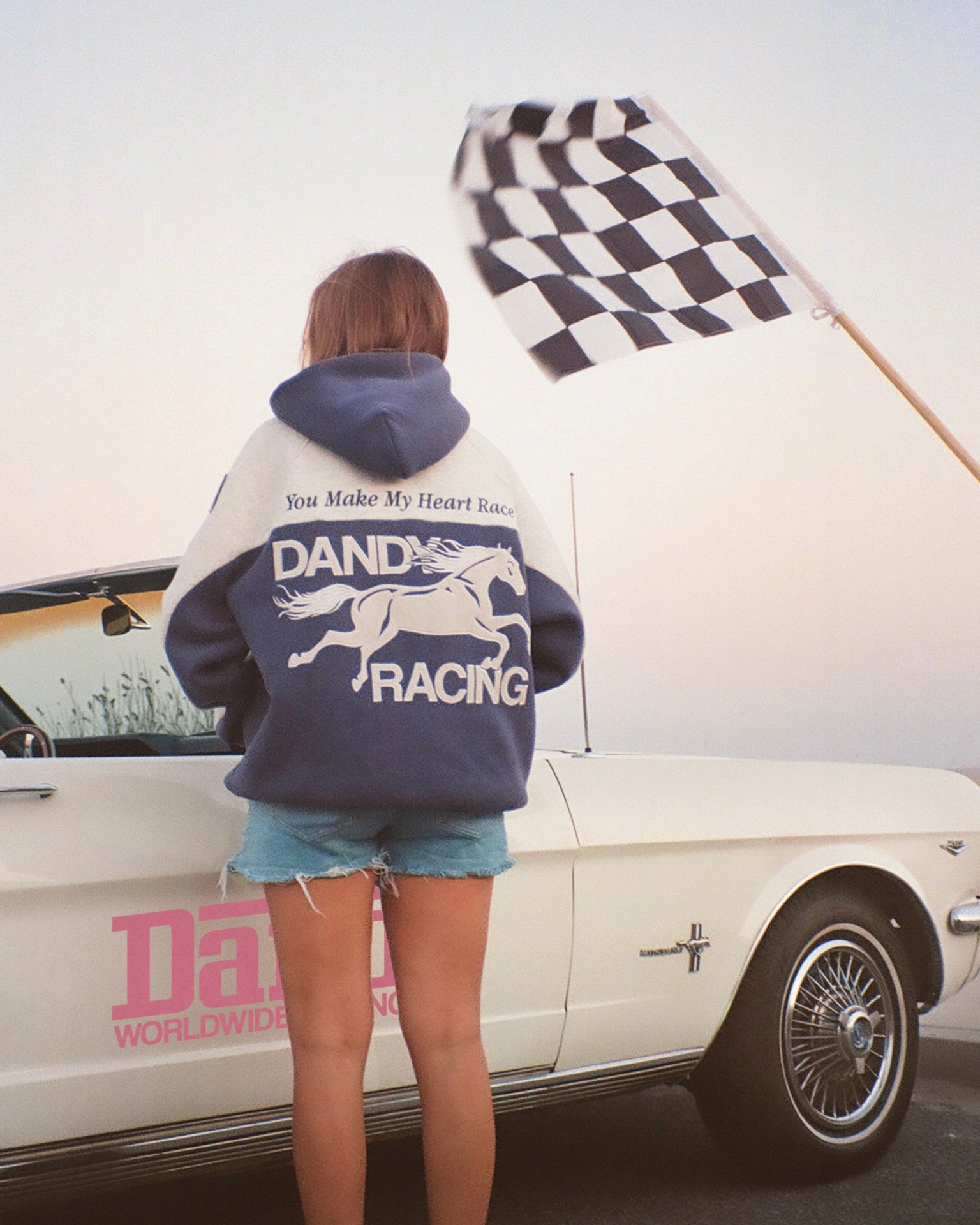 "Racing Heart" Oversized Lux Hoodie in Blue standing next to a vintage car at the beach