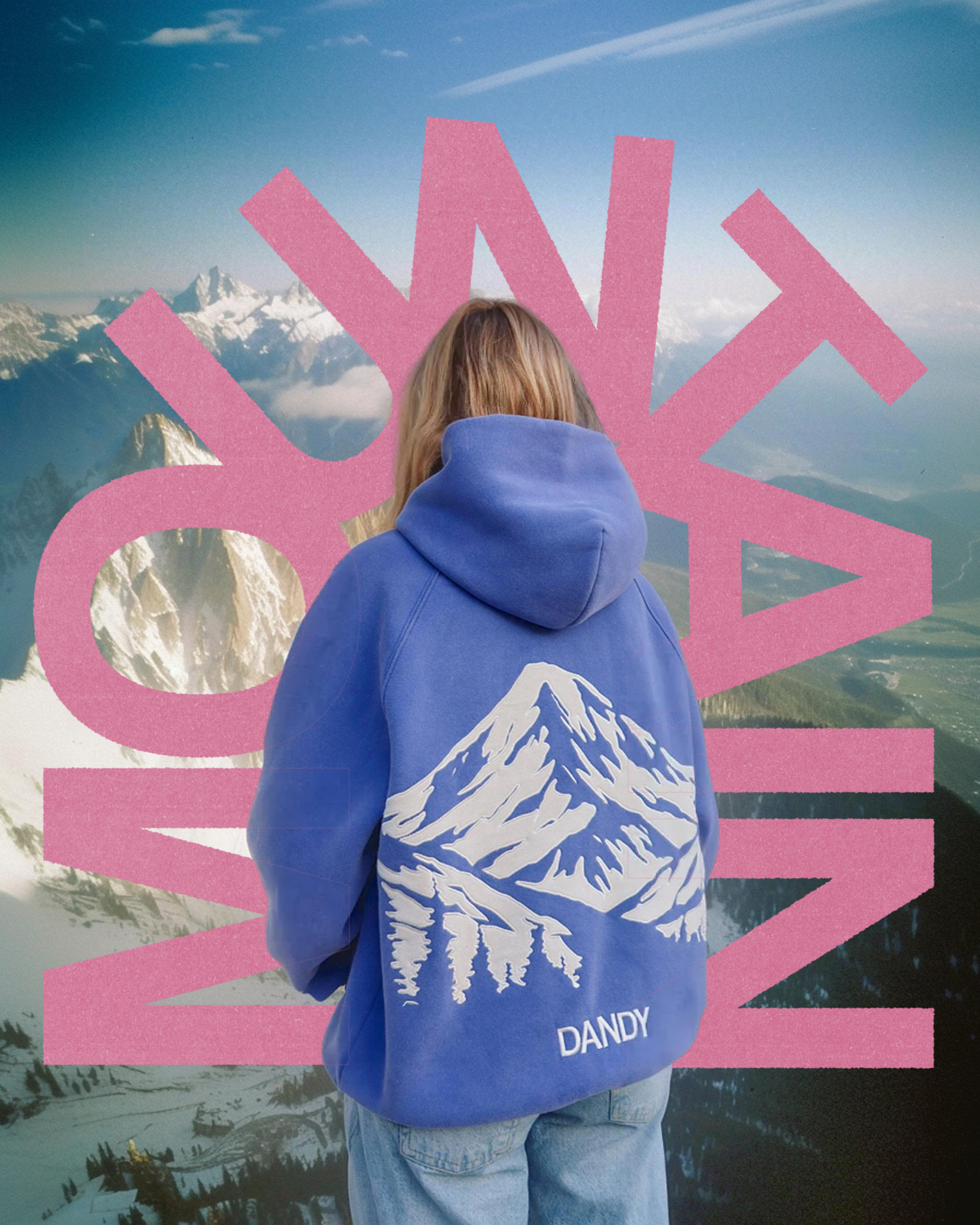 Person wearing a blue hoodie with mountain design in front of a scenic mountain landscape.
