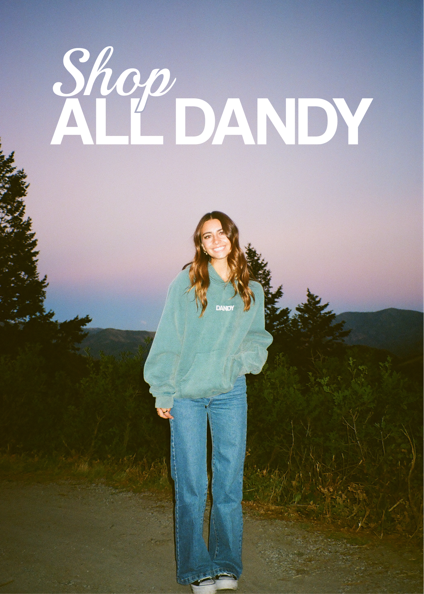Clickable image with 'Shop ALL DANDY' text overlay and a Girl wearing a teal sweater and blue jeans standing outdoors in a mountain setting.