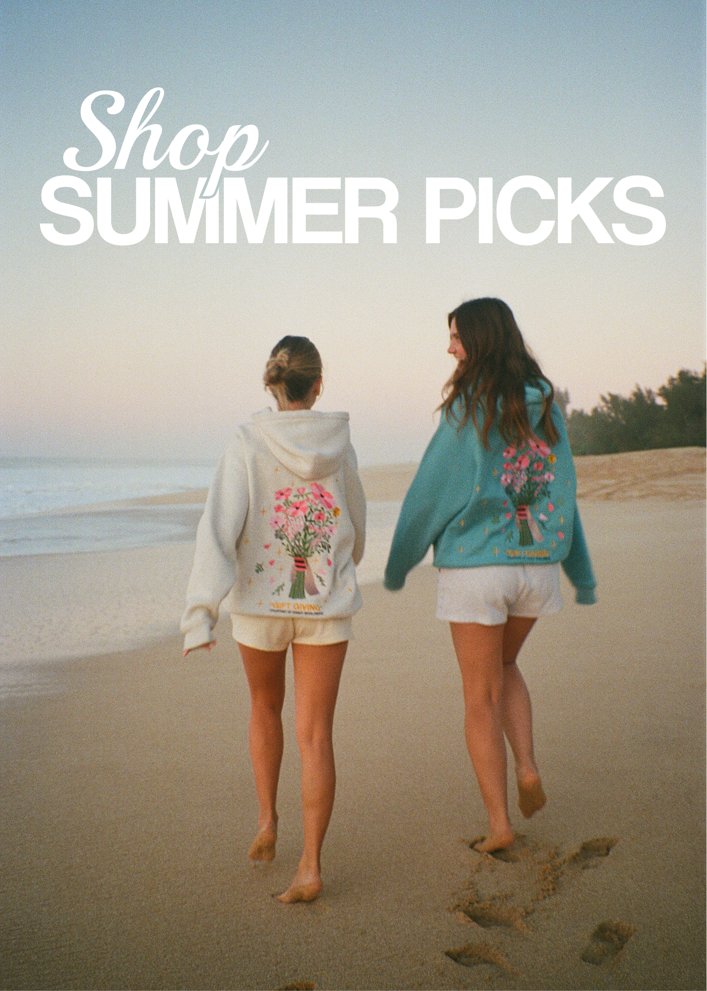 CLICKABLE IMAGE THAT READS: "Shop Summer Picks"
 Two people walking on a beach wearing a heather grey hoodie and a blue hoodie with flowers on the back.