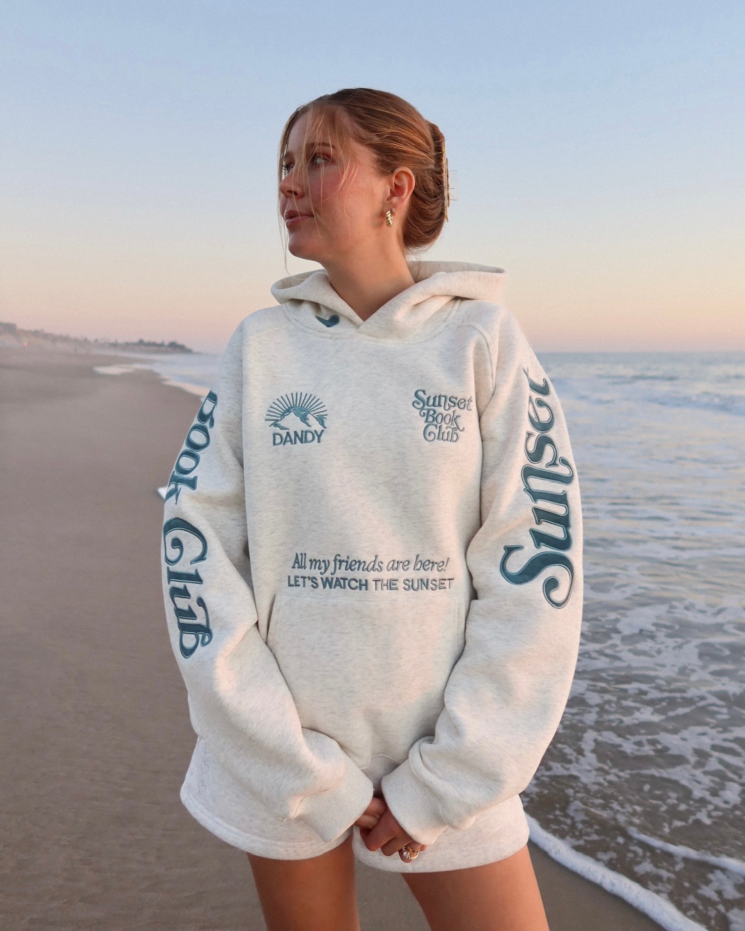 Person wearing a hoodie with text on a beach