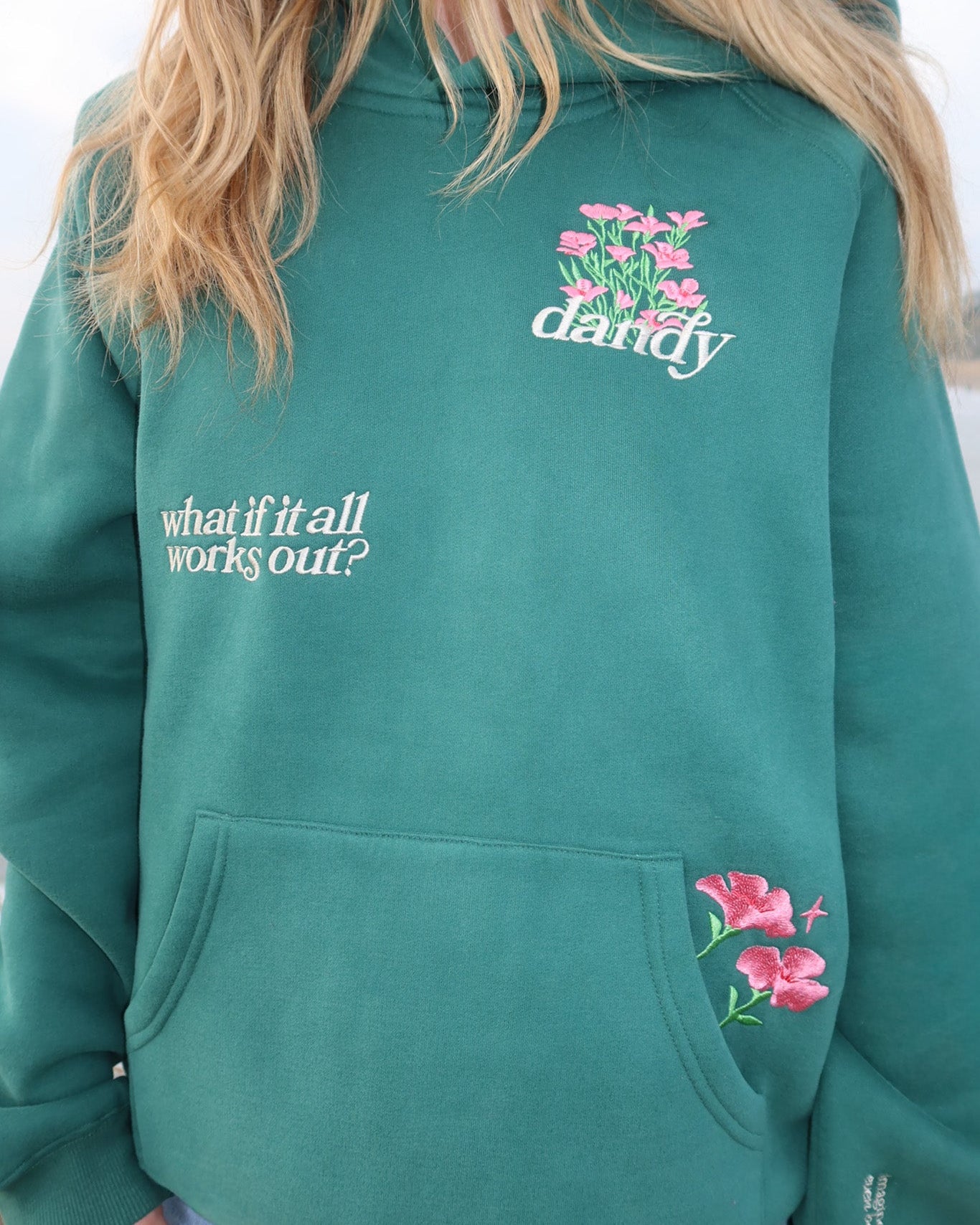 Green hoodie with floral designs and text on a plain background