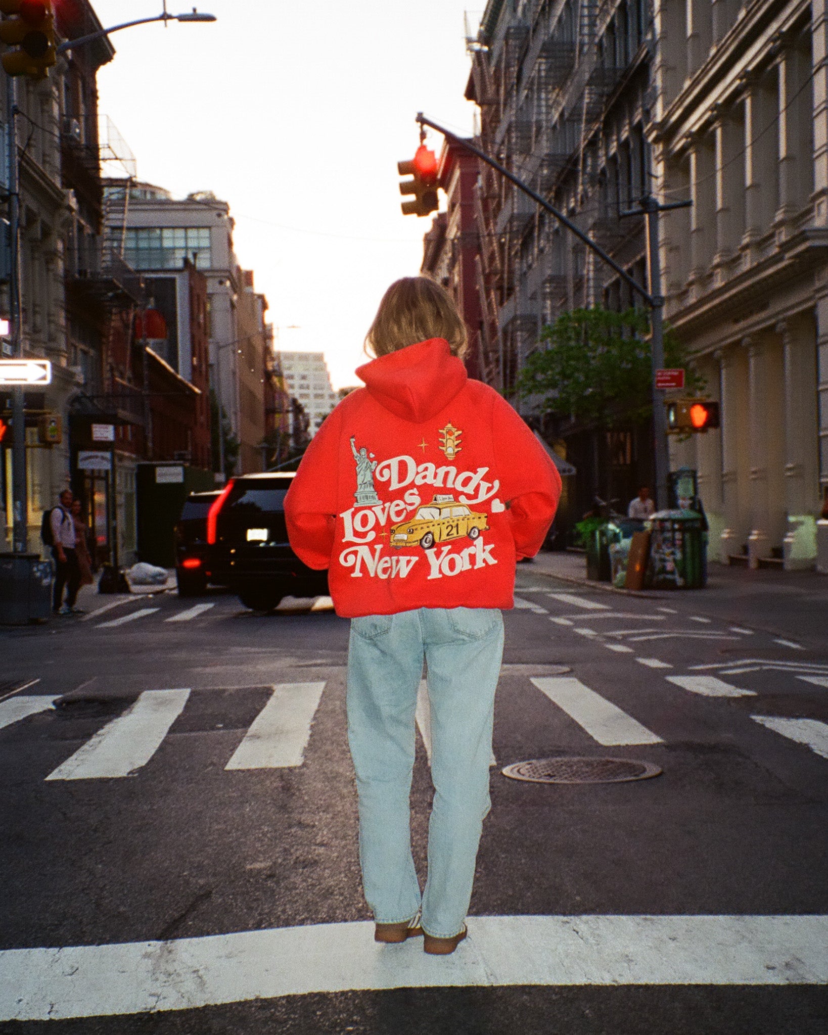 Person wearing a red hoodie with text standing on a city street