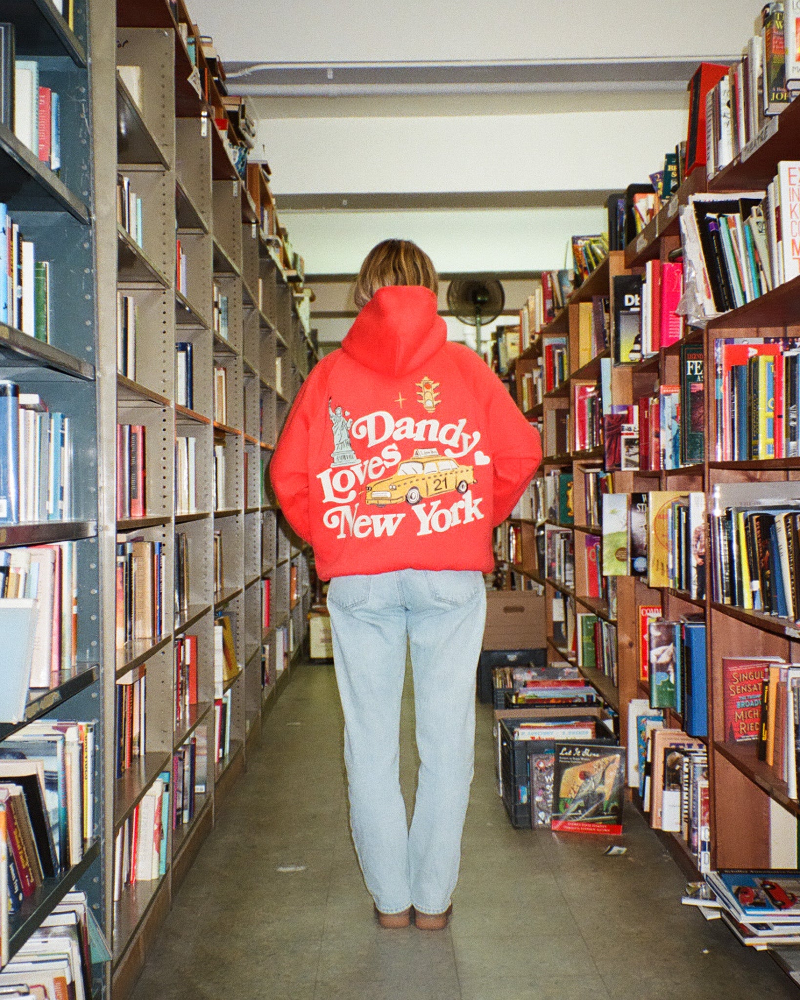 Person wearing a red hoodie with text in a bookstore