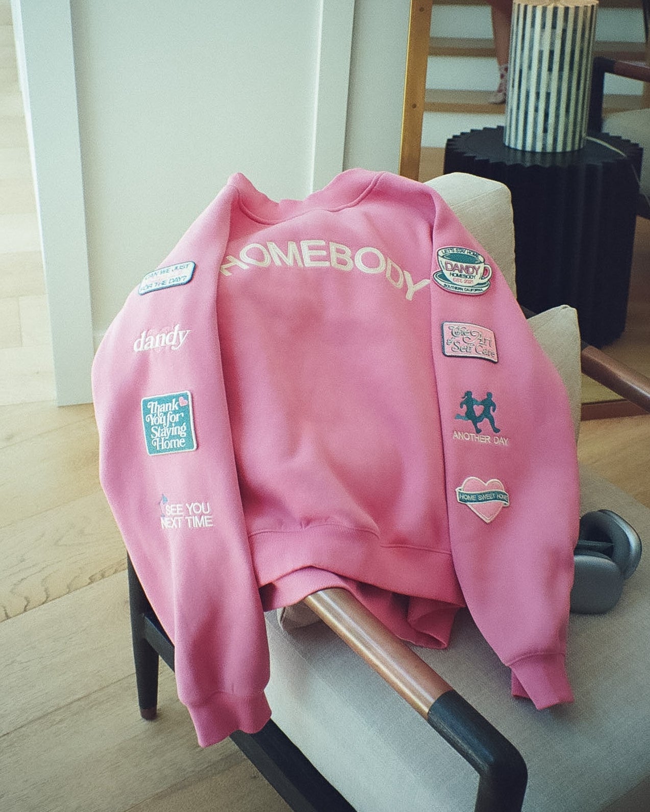 Pink sweatshirt with patches on a chair in a room