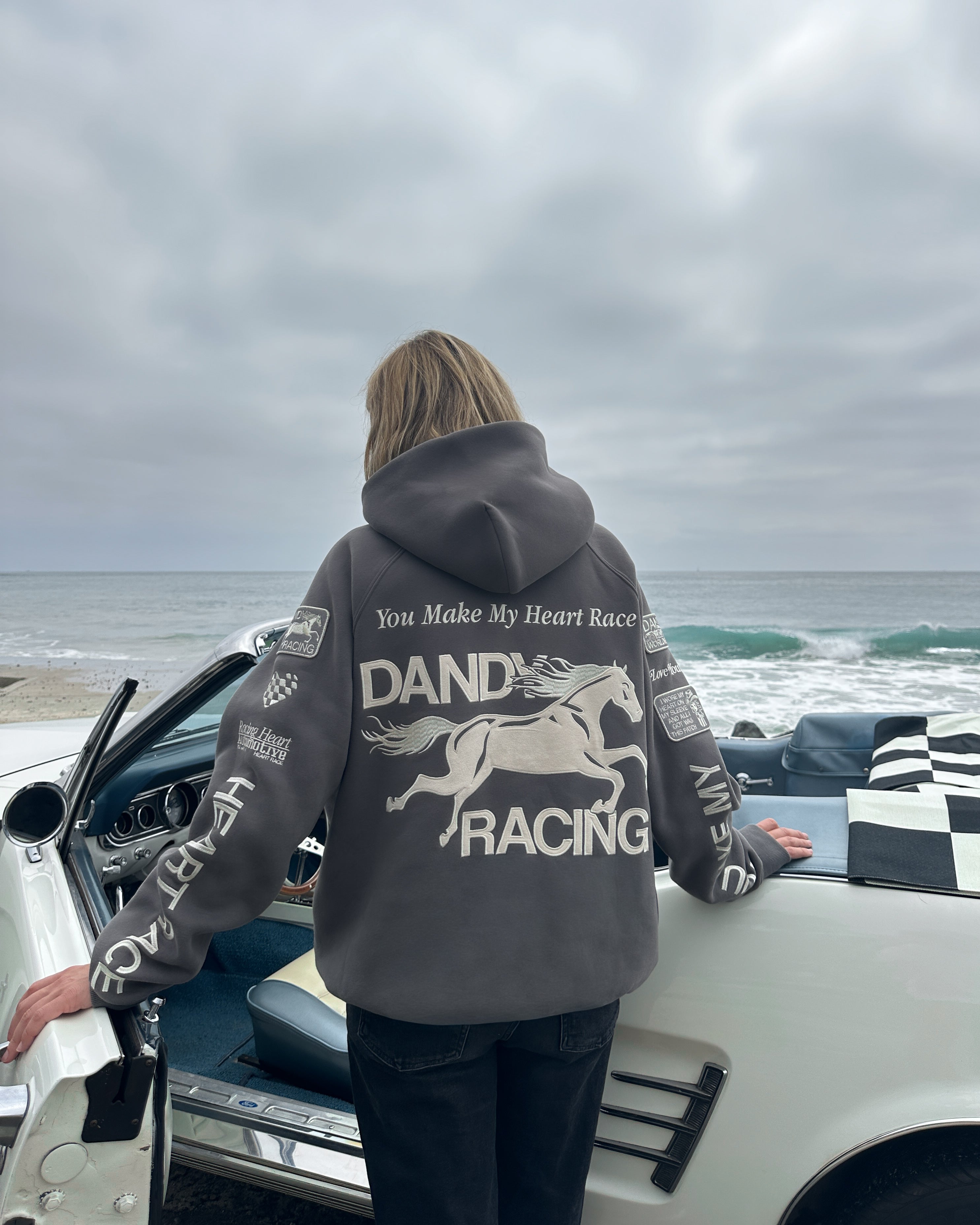 "Racing Heart" Oversized Lux Hoodie in Dark Gray opening the front door of a vintage car