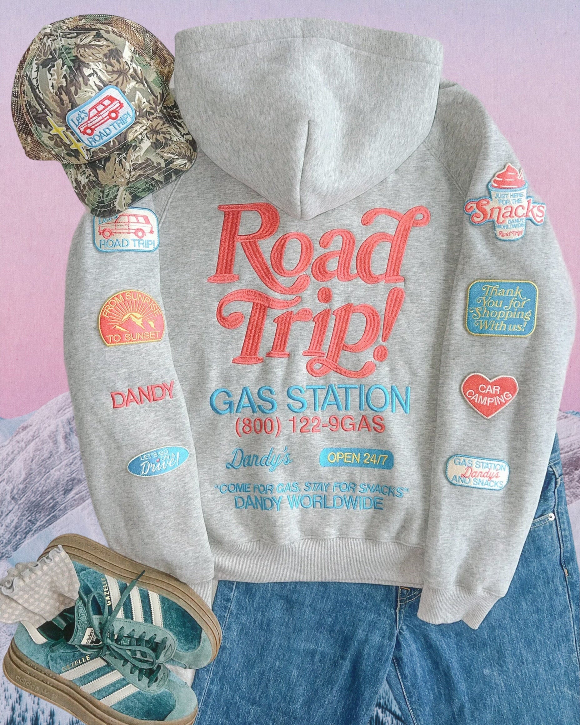 Gray hoodie with 'Road Trip!' text and vintage gas station graphics on a pastel background