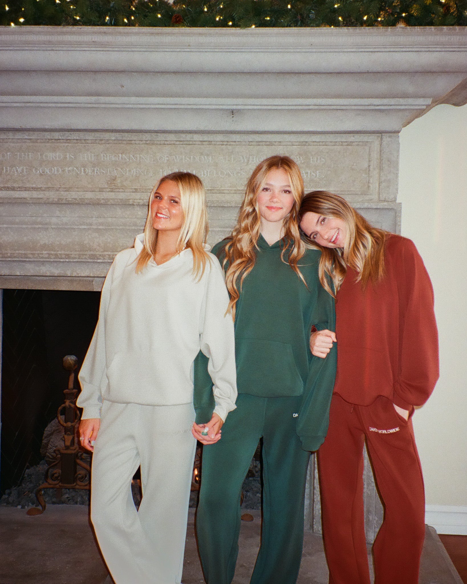 Three women in matching outfits standing in front of a fireplace.