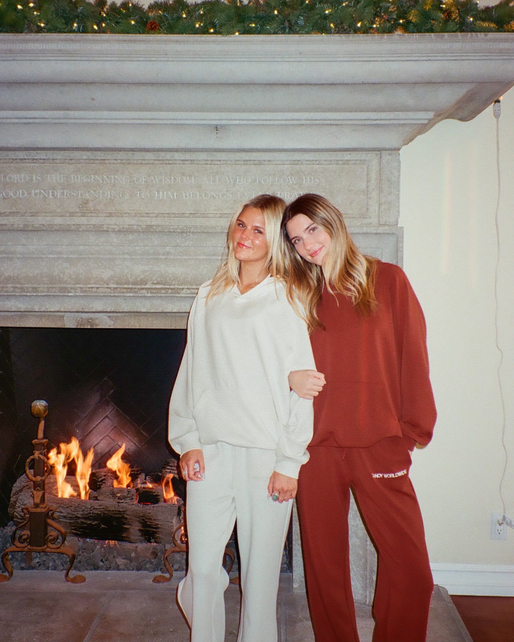Two people standing in front of a fireplace wearing matching outfits.