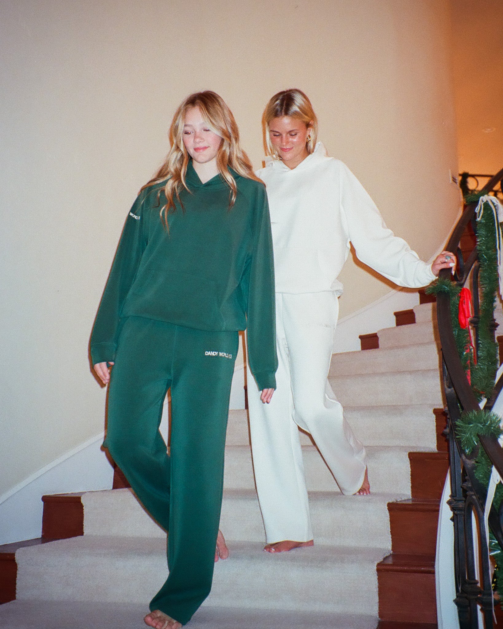 Two women in green and white tracksuits standing on a staircase.