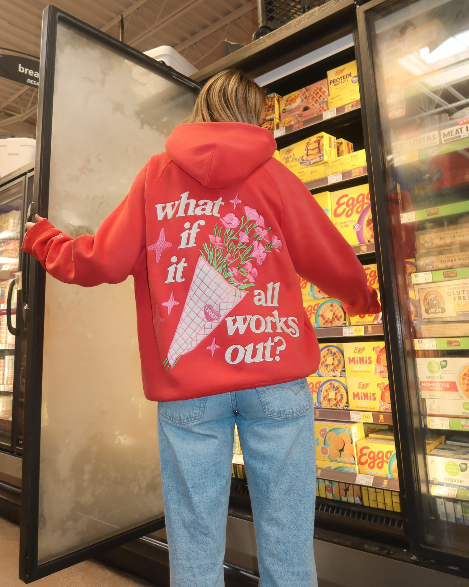 Person wearing a red hoodie with a message in a grocery store