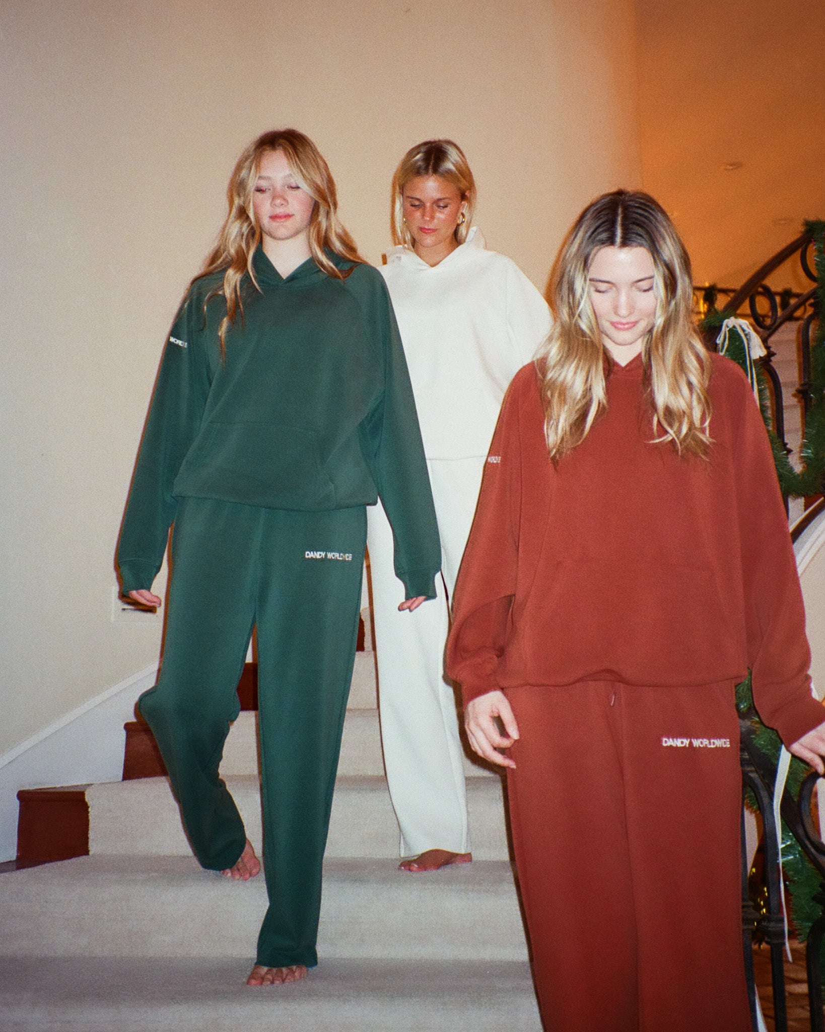 Three people wearing tracksuits walking down a staircase.