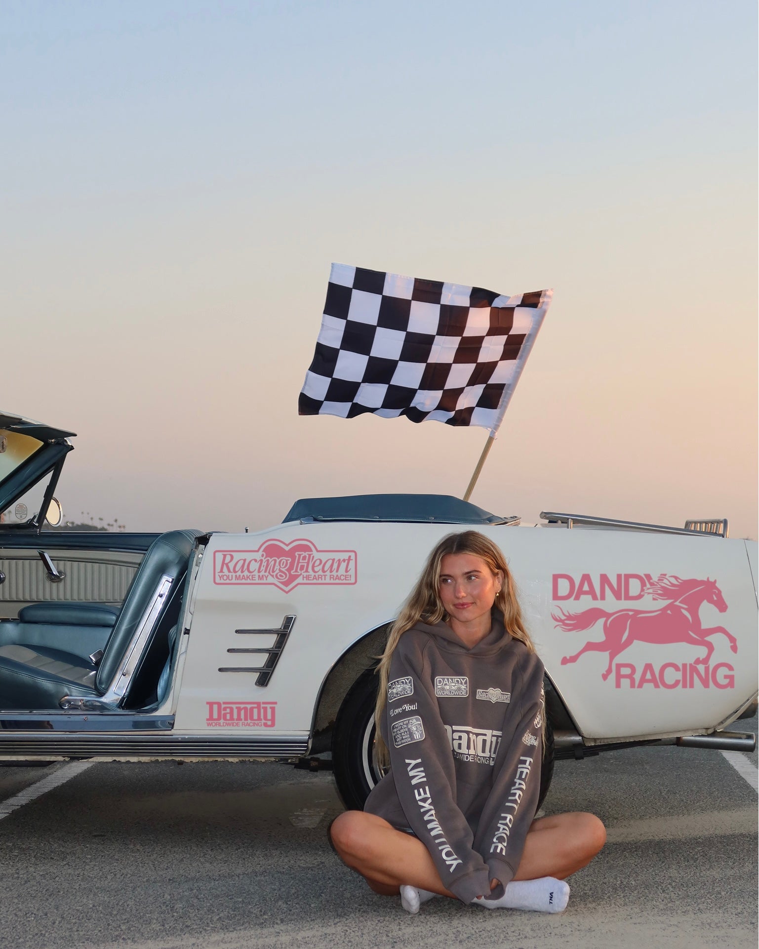 "Racing Heart" Oversized Lux Hoodie in Dark Gray sitting next to a vintage car at the beach at sunset