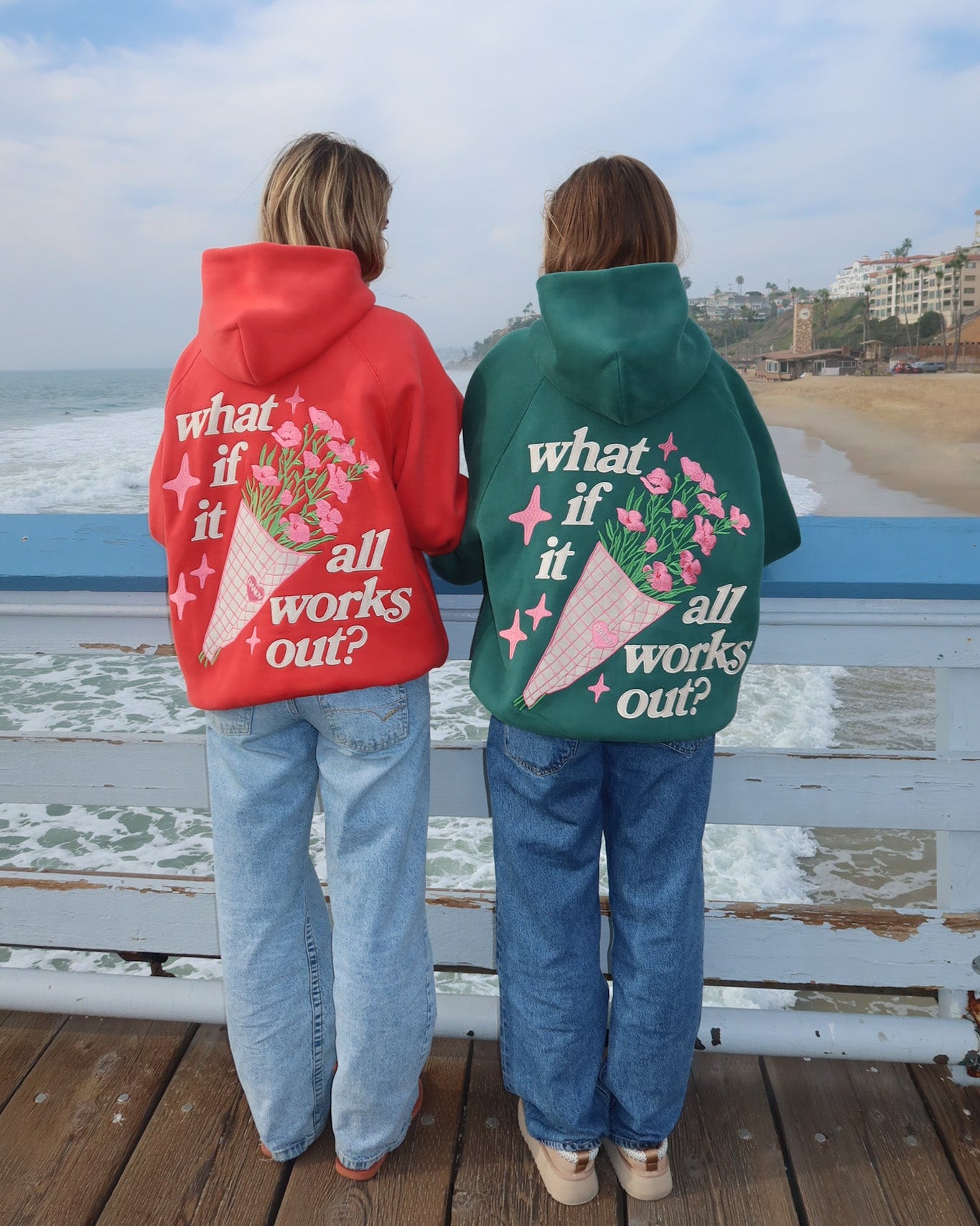 Two people wearing hoodies with a beach and ocean view.