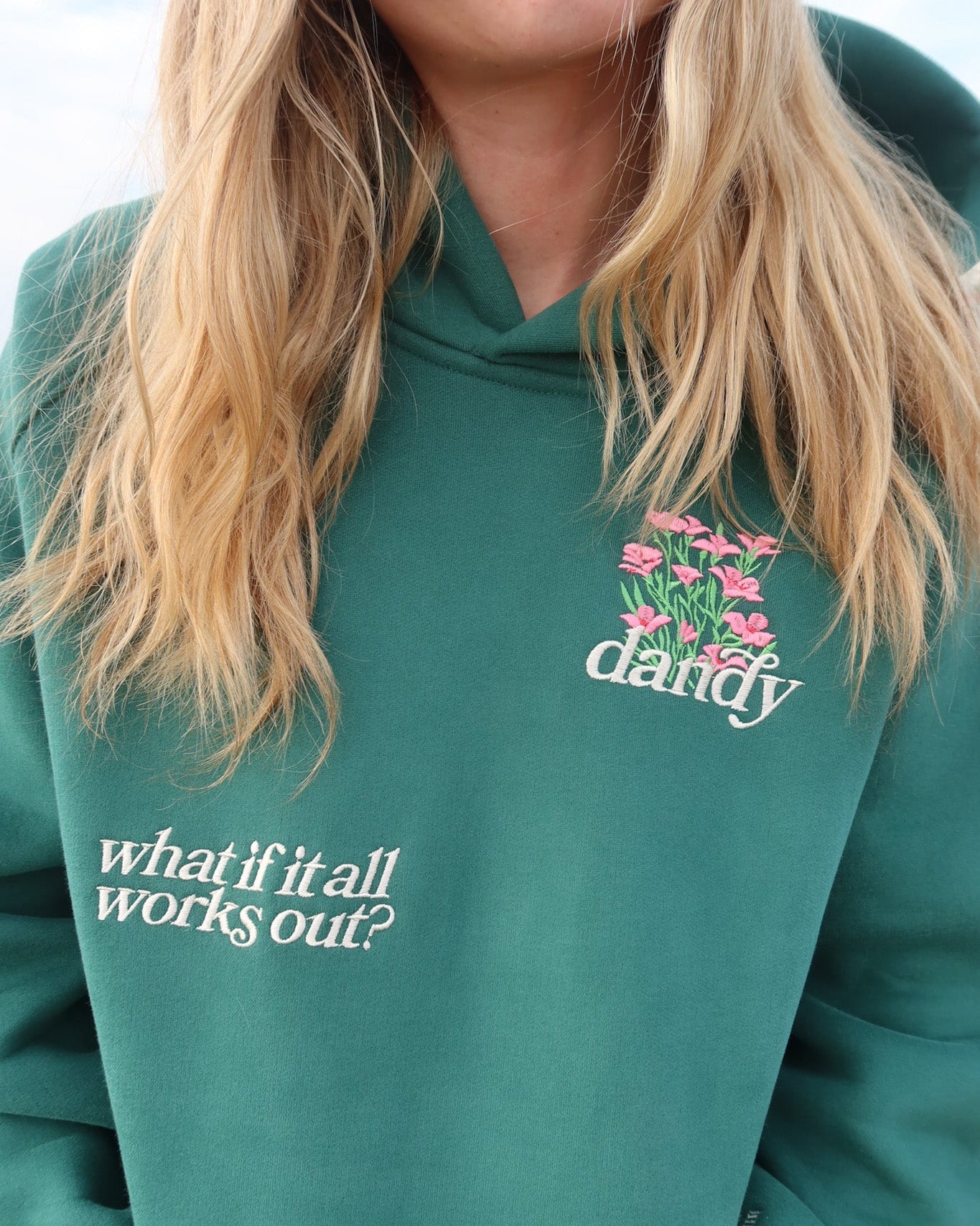 Green hoodie with text and floral design on a blurred background