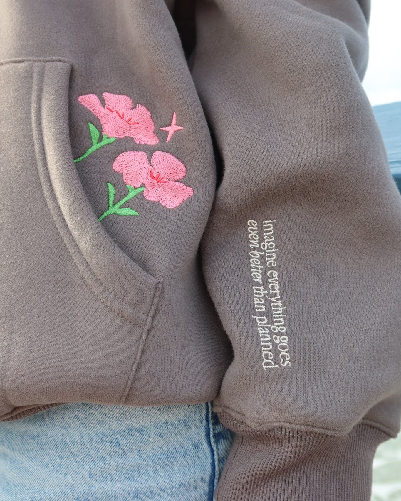 Gray hoodie with floral design and text on sleeve