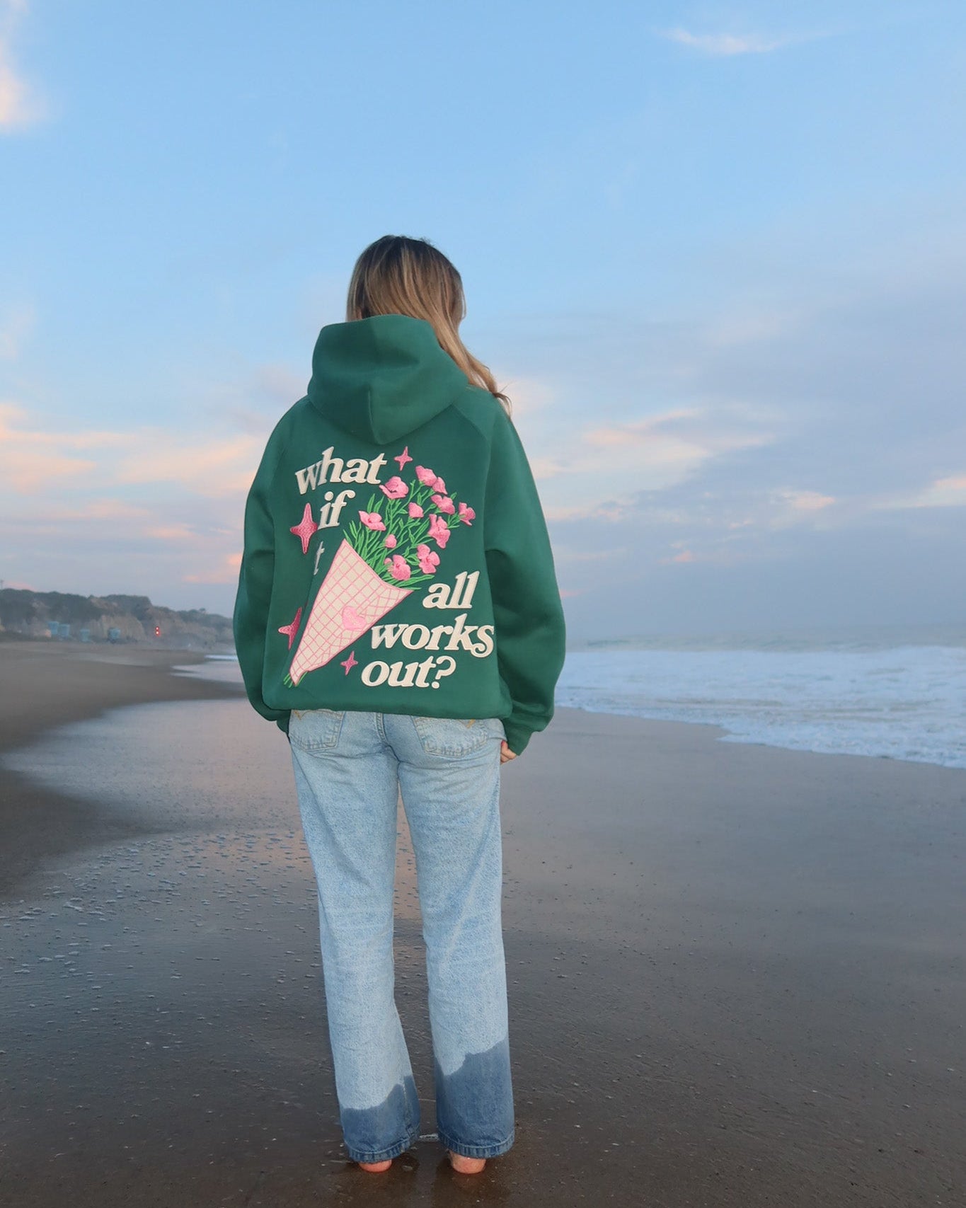 Person wearing a green hoodie with a quote on the beach