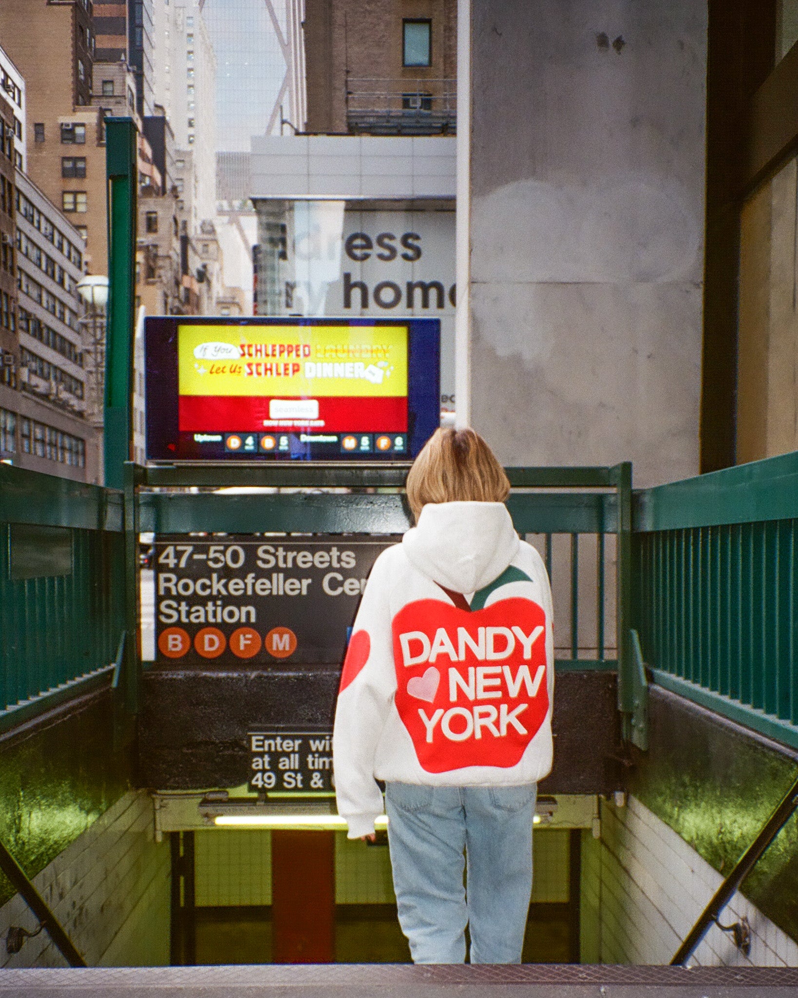 Person wearing a hoodie with 'Dandy New York' on it standing in a subway station.