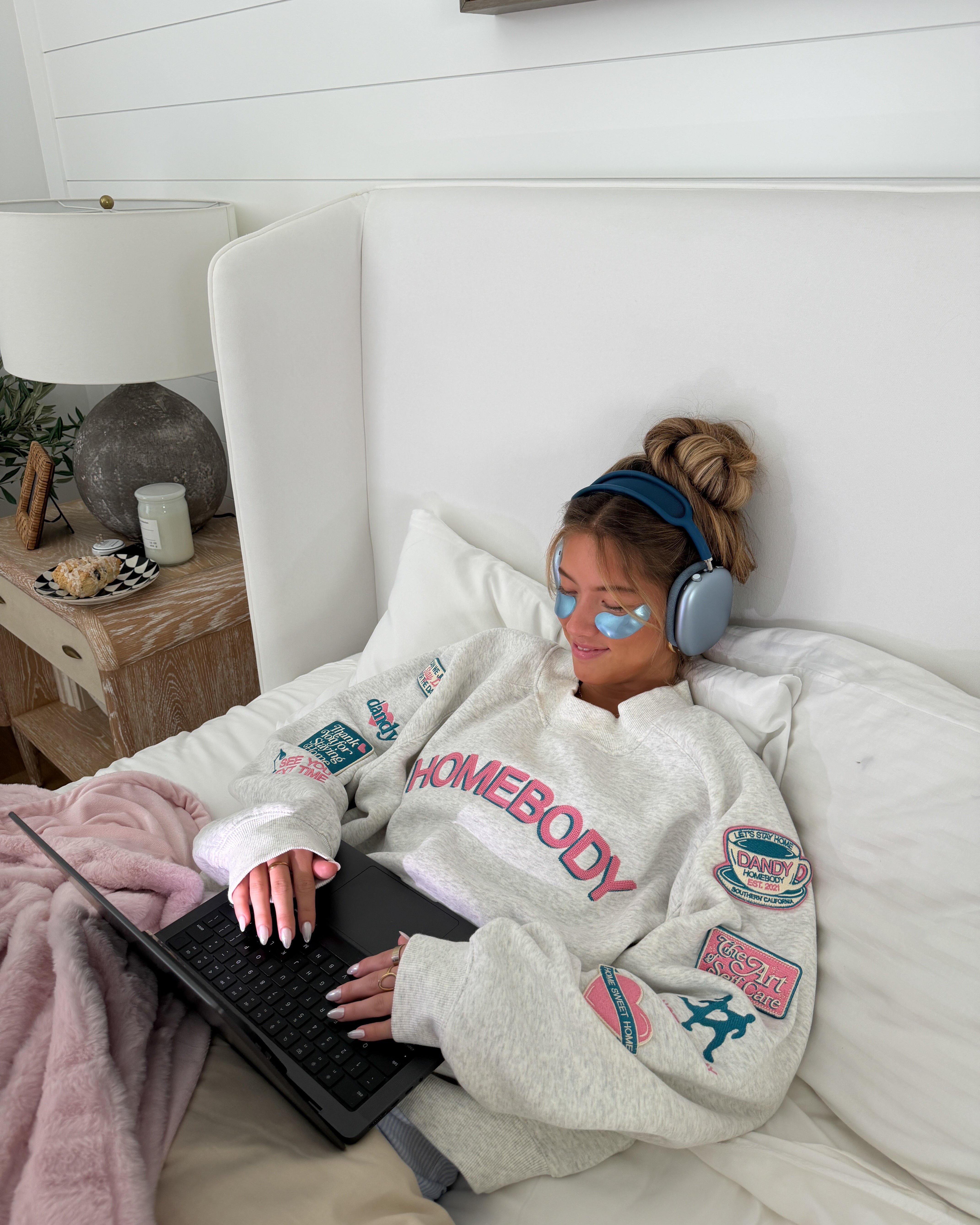 Person lying on a bed using a laptop with a cozy atmosphere