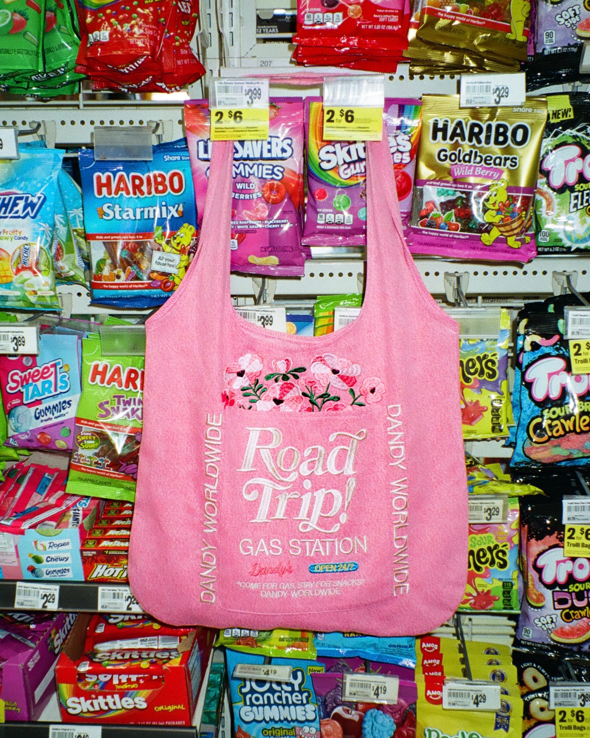 Pink reusable bag with 'Road Trip! Gas Station' text in a candy store setting